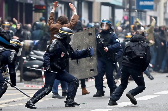 French CRS riot policemen pursue demostrators during a demonstration by French state-owned railway company SNCF workers and students in Paris as part of a nationwide strike