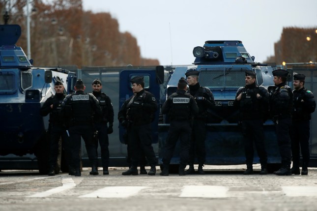 French Gendarmes stand next to armoured vehicles in place on the Champs-Elysees Avenue during a national day of protest by the "yellow vests" movement in Paris