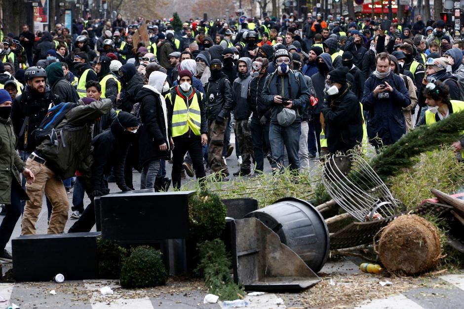 Protesters wearing yellow vests install a barricade during clashes with police at a demonstration during a national day of protest by the "yellow vests" movement in Paris
